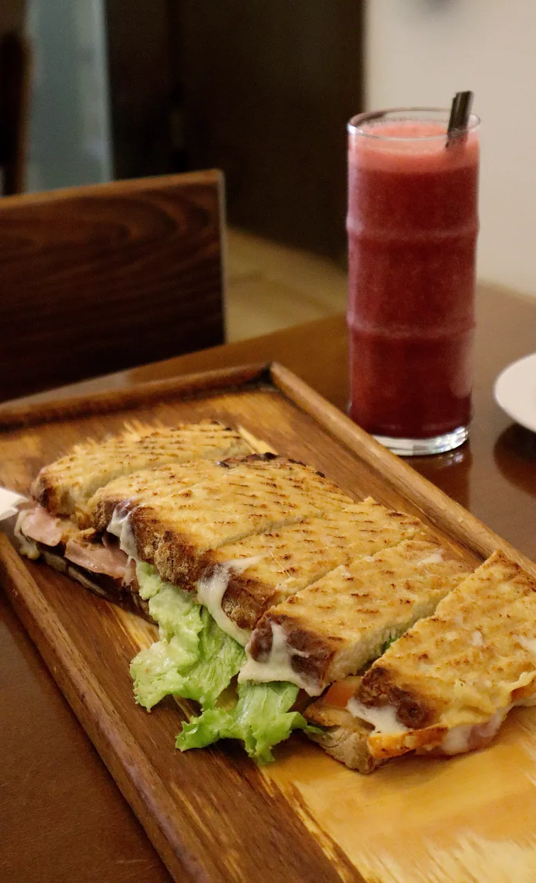 Tosta grelhada em tábua de madeira, com sumo natural ao fundo