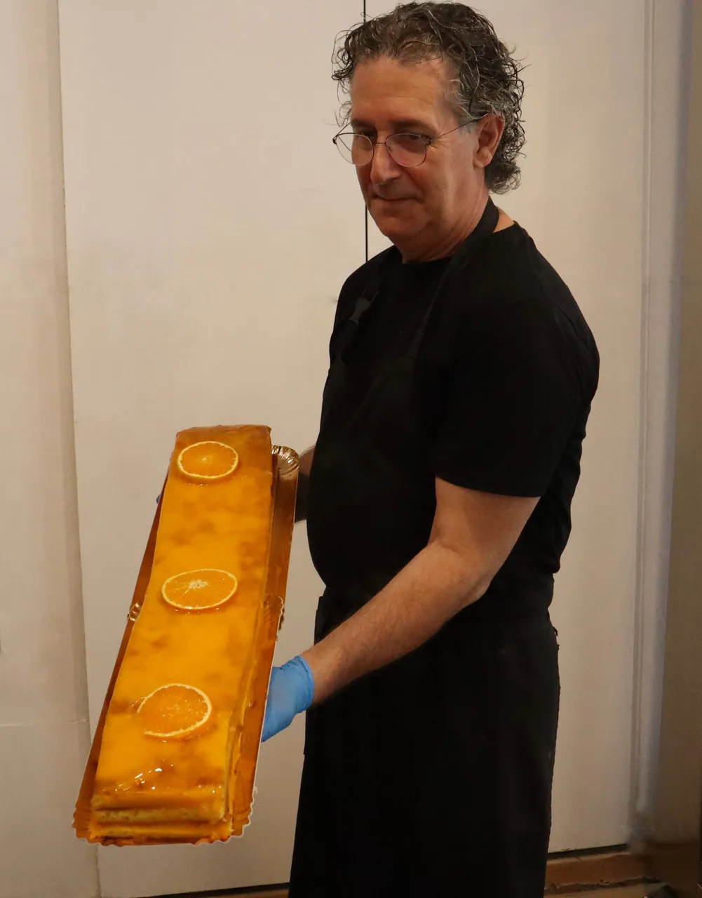 Funcionário a segurar um bolo de laranja de um metro