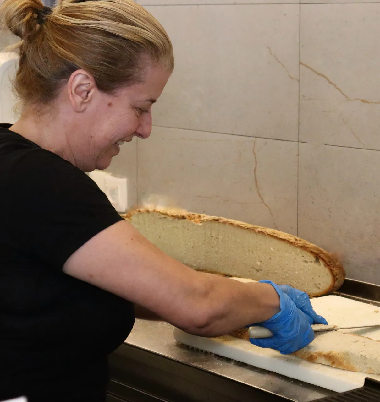 Funcionária a preparar o pão artesanal de um metro no balcão
