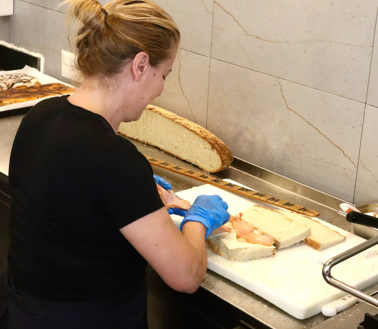 Funcionária a montar uma tosta a metro na tábua