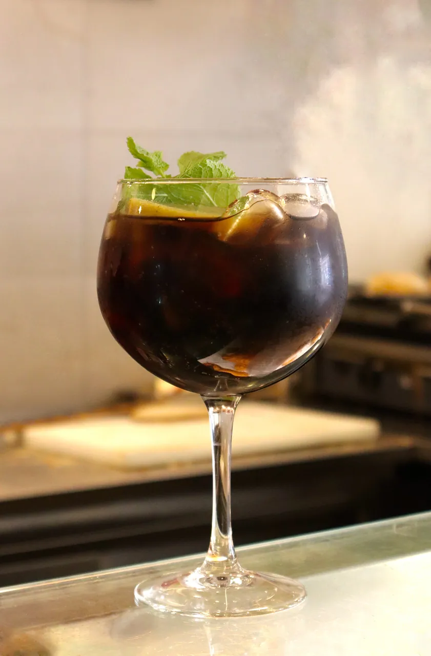 Sangria fresca servida num copo de balão, com hortelã