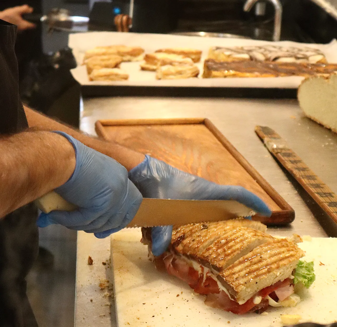 Funcionário a cortar uma tosta grelhada na tábua de madeira