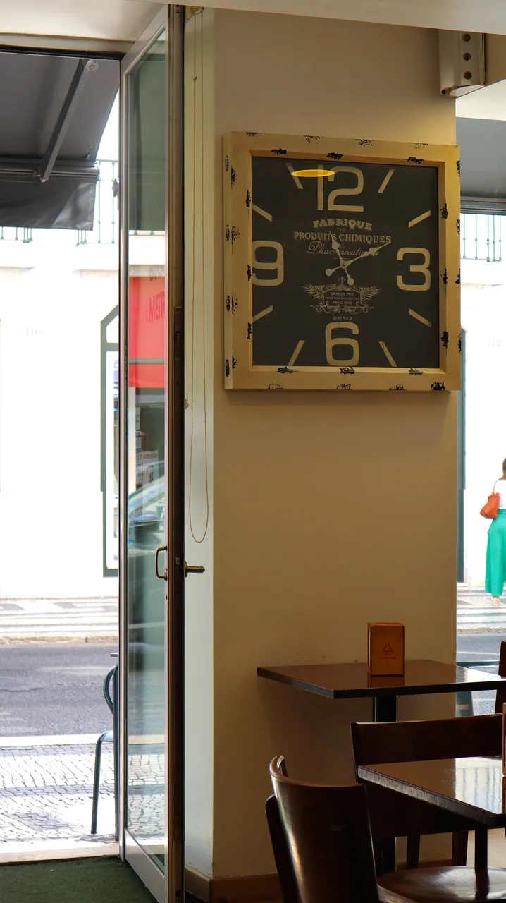 Interior do café, com relógio de parede vintage e mesas