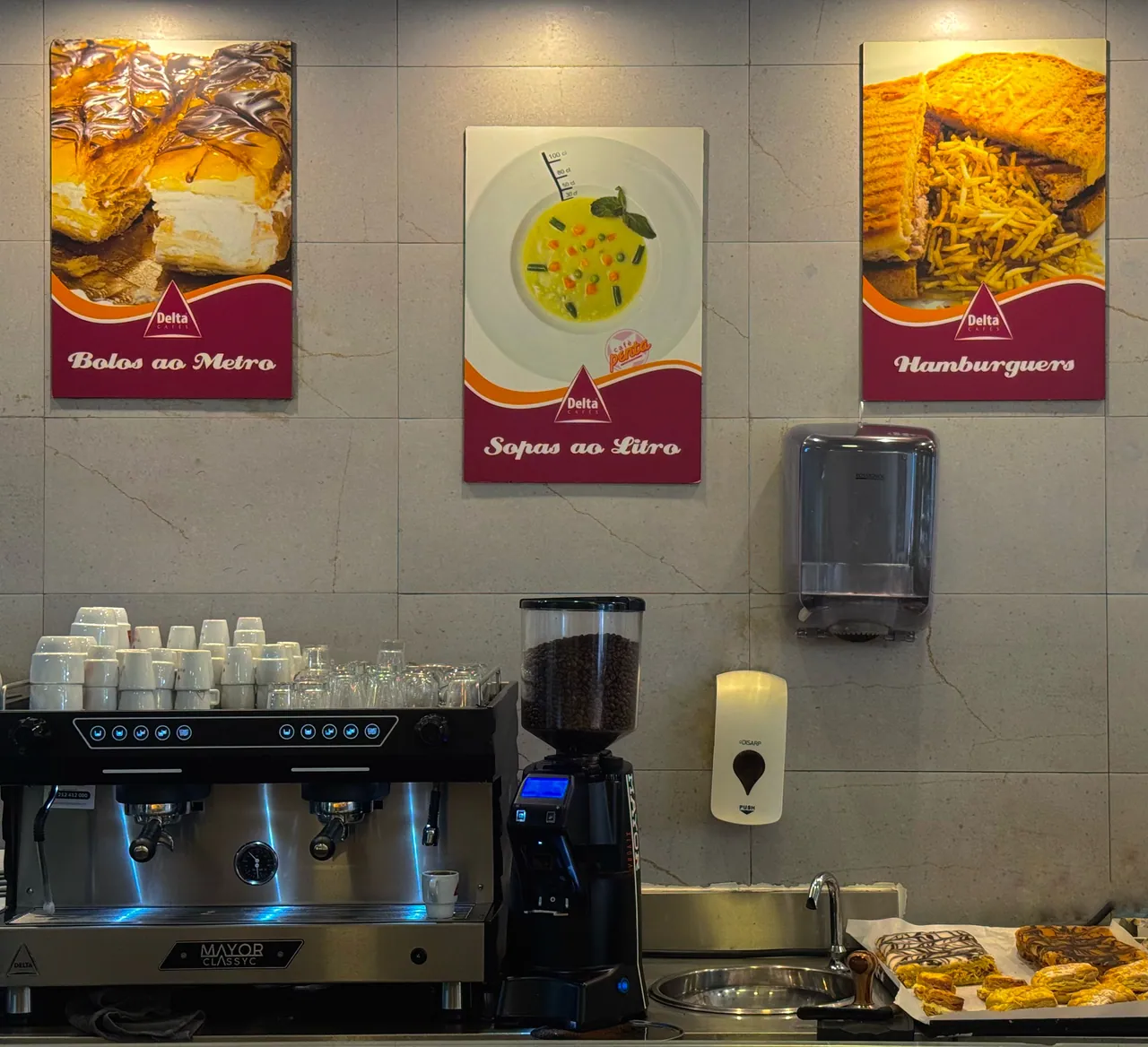 Balcão com a máquina de café e os cartazes da casa