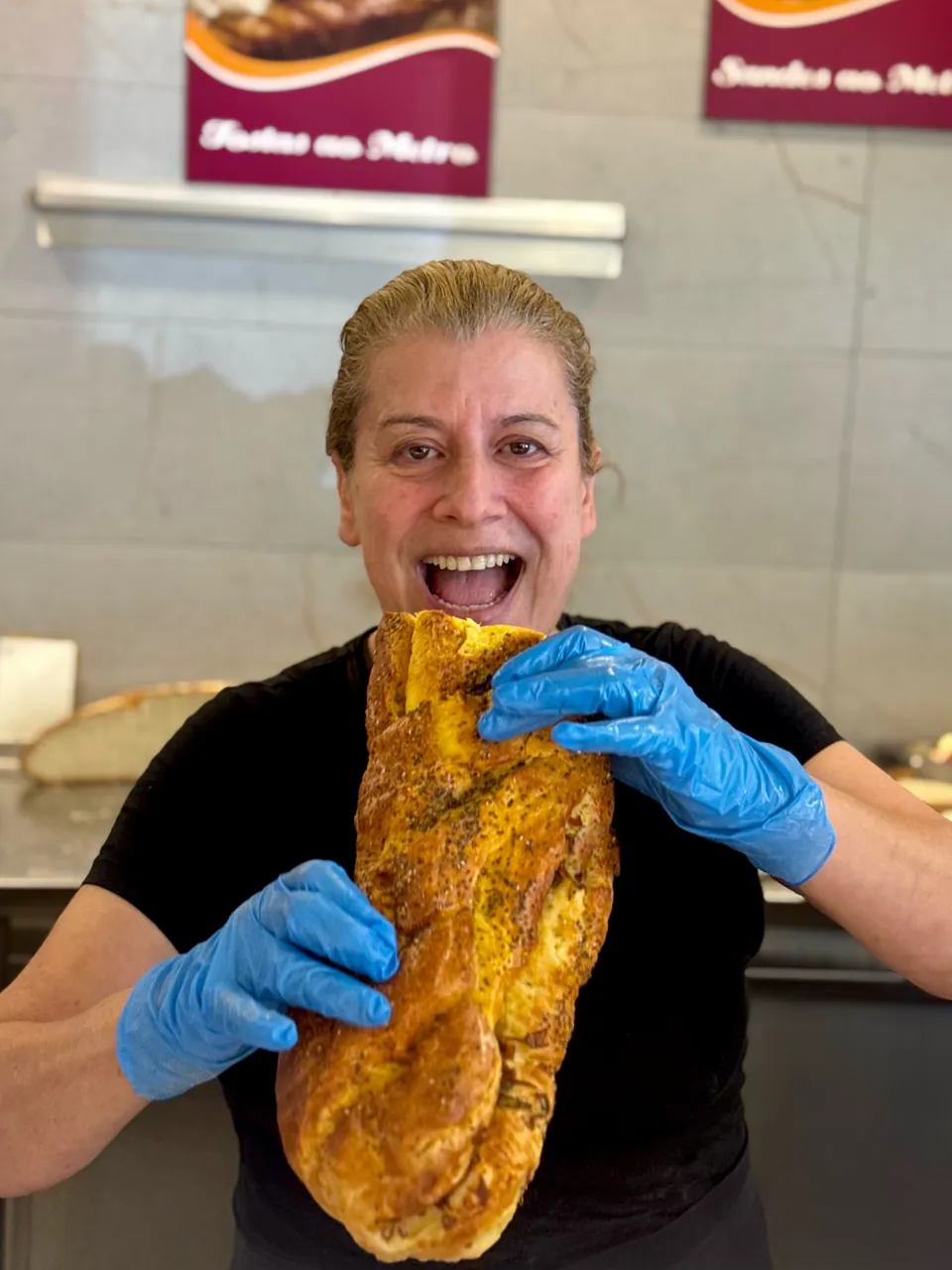 Funcionária a trincar uma tosta grande, a rir